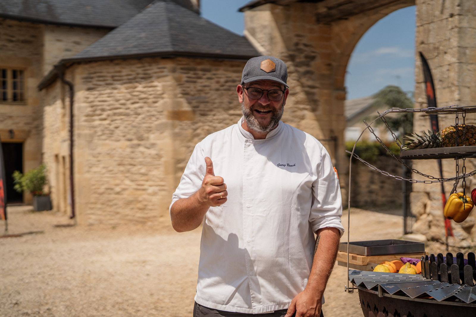 Georg Bauch junto a um grelhador de fogo aberto no pátio de um château francês